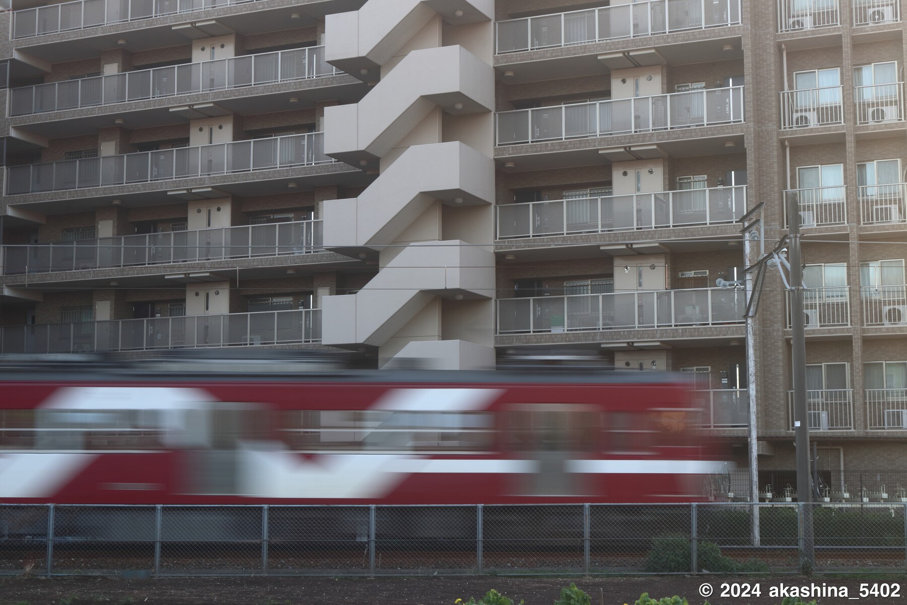 マンションを背景にはしる「あかぎ」