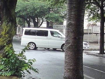 右手の街路樹の右側に、セダンの鼻先が出てます
