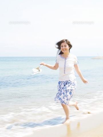 女性が、脱いだサンダルを片手に持って