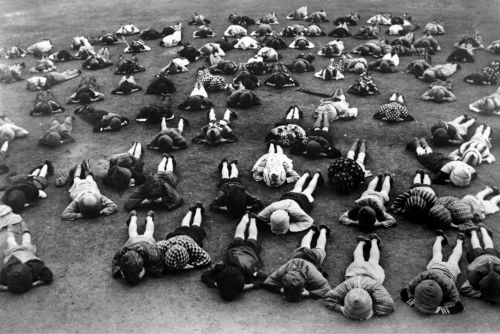 防空頭巾で地面に伏せる子どもたち1943年