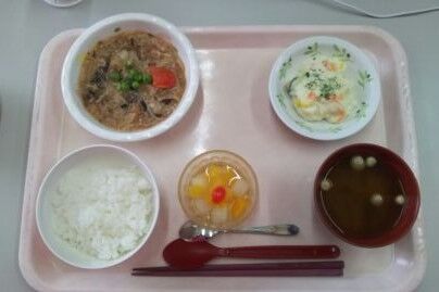 介護施設の食事トレー。ご飯、おかず、汁物、デザートが配置されている。