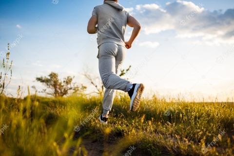 close-up-of-sportive-man-jogging-in-field-at-sunrise_176420-5186