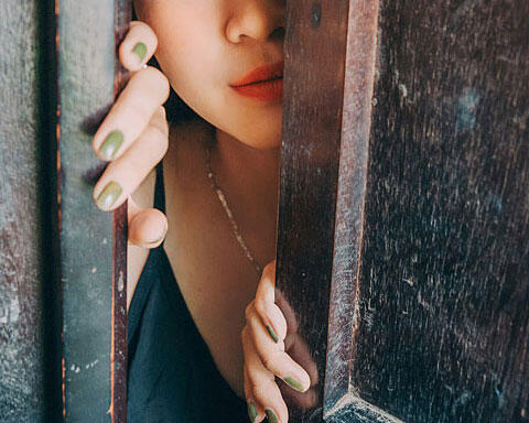 ドアの隙間から顔を出す女性