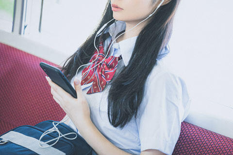 通学中にスマホで音楽を聴く女子高生