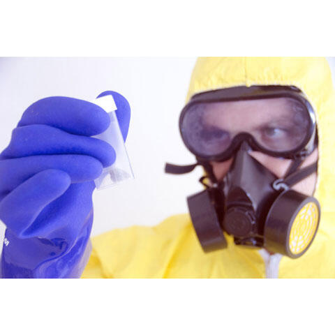 防護服とガスマスク姿で容器に入った危険物を見る科学者