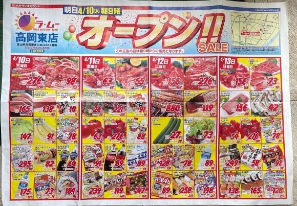 The image shows a colorful Japanese supermarket flyer advertising a grand opening sale from April 10th to April 13th. The flyer is divided into five columns, each representing a different day with various food items such as meat, seafood, vegetables, and packaged goods, all marked with prominent prices in large red and black numbers. At the top, bold Japanese text announces the opening, accompanied by a small map on the upper right corner showing the store location. Bright yellow and red backgrounds highlight some of the deals, making the flyer visually busy and attention-grabbing.