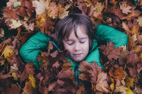 Boy laying amoungest fall leaves