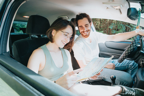 two-people-in-a-car-look-at-a-map-while-smiling