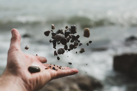 hand-tossing-pebbles_925x