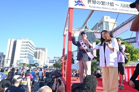 ランナーに笑顔で手を振る仲間由紀恵さん（右端）と知念覚市長（右から2人目）＝7日午前9時6分、那覇市内