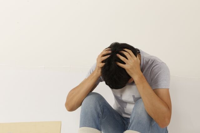 頭を抱えて落ち込む男性