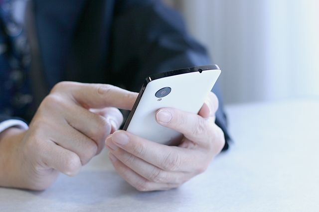 スマホを操作するスーツを着た男性の写真画像