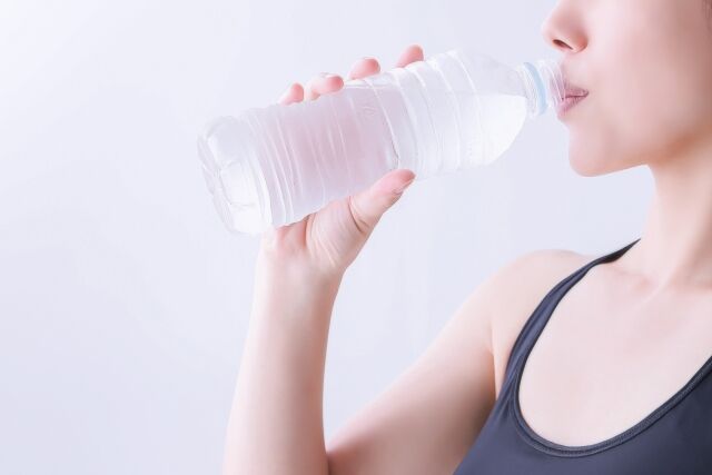 ペットボトルの飲料水を飲む女性