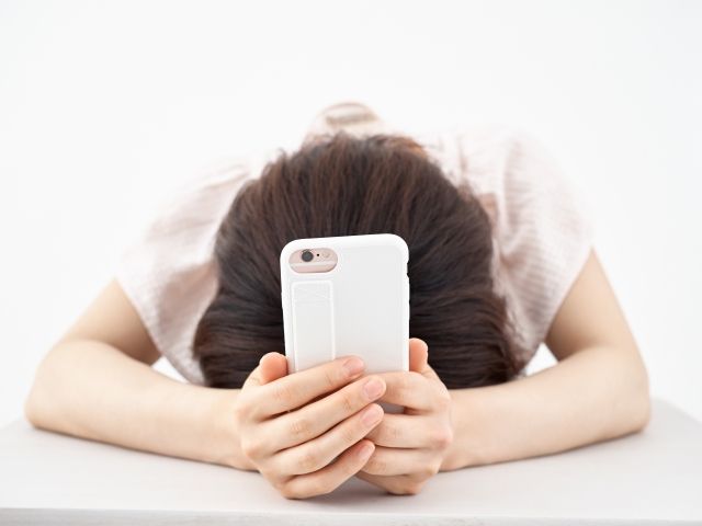 スマホを持ってがっかりする女性