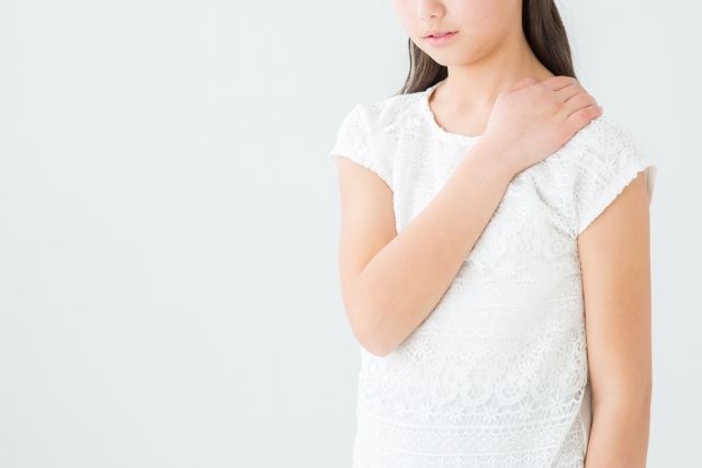 肩を押さえる小学生の女の子
