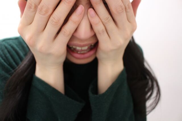 目を隠して口を開けて泣く女性