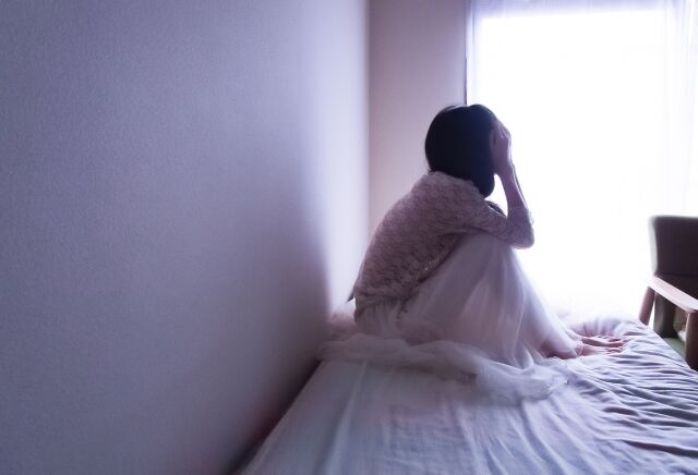 ベッドの上で泣く女性