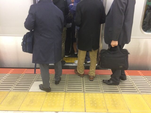 満員電車の乗り込むスーツの男性ら