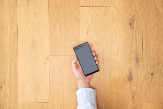 スマホを持って手を伸ばす男性