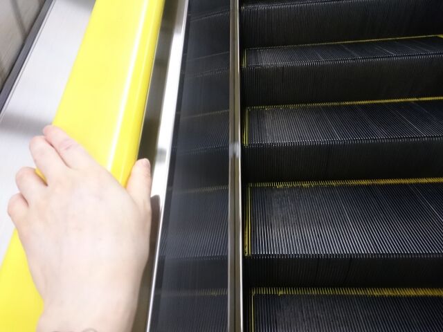 エスカレーターと男性の手