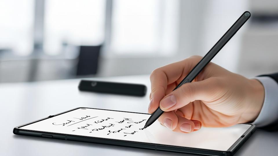 Razr Fold에 글씨를 쓰는 Moto Pen Ultra를 들고 있는 손.