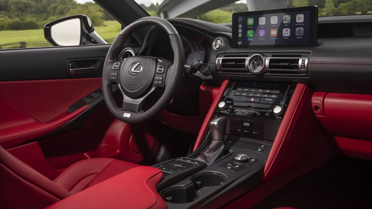 2024年型レクサス IS 350 F SPORTのキャビン内で撮影され、赤いレザーのインテリア、ステアリングホイール、ダッシュボードが示されています。