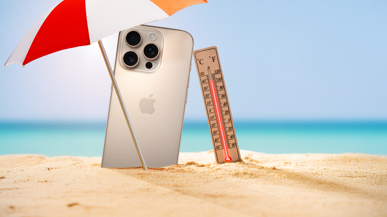 海を背景に、ビーチ パラソルの下の砂の上に置かれた iPhone と温度計。