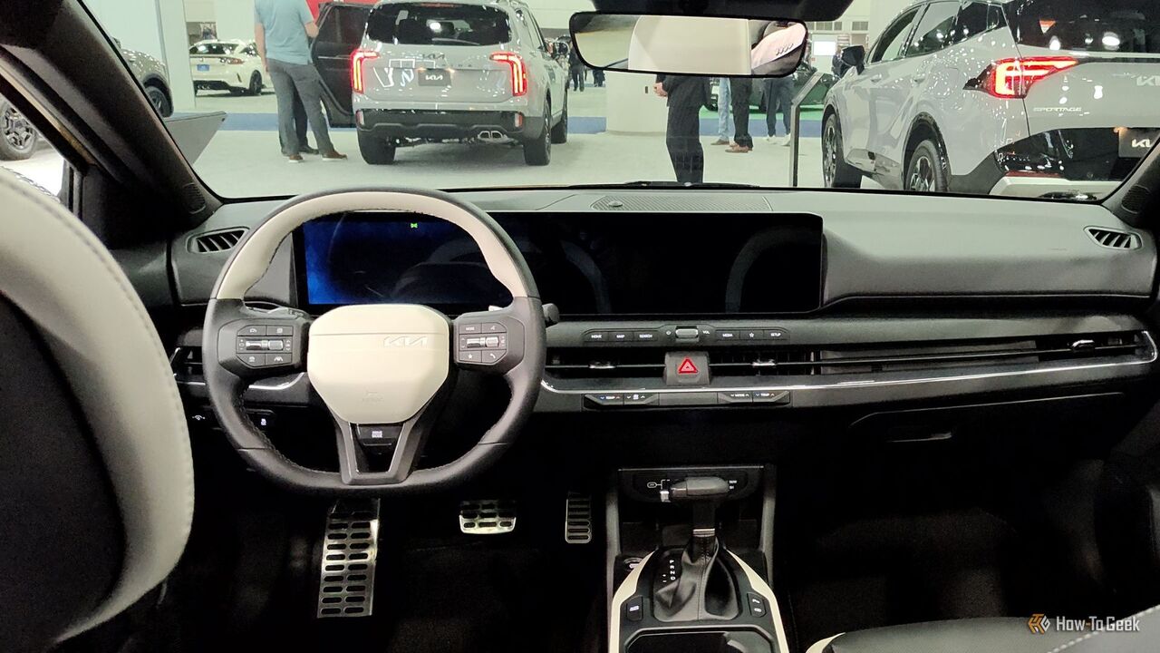 2026 Kia K4 ハッチバックのキャビン内のステアリング ホイールとダッシュボードのショット。