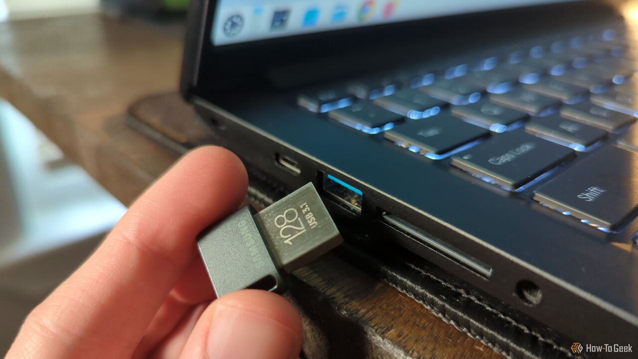 USB ドライブをラップトップのポートに差し込む人の手。