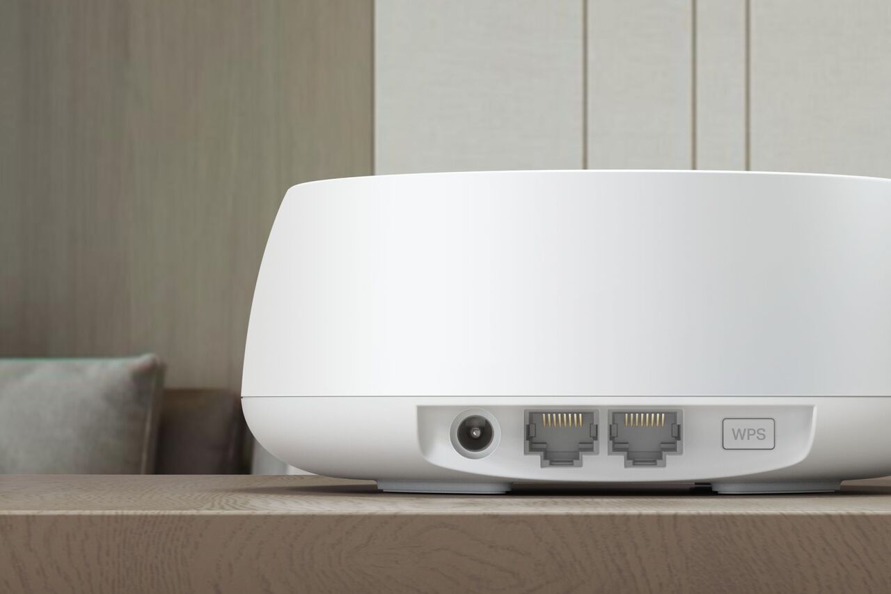 木製の机の上に置かれた TP-Link Deco BE5000 Wi-Fi 7 メッシュ デバイス。背面ポートが示されています。