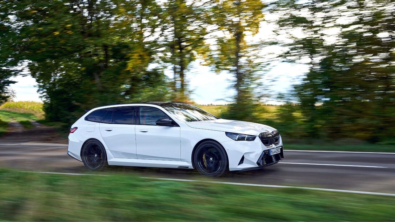 白い BMW M5 ツーリングのダイナミックな側面ショット。