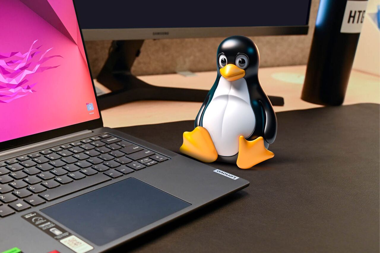 ラップトップの隣の机の上の Linux マスコット。