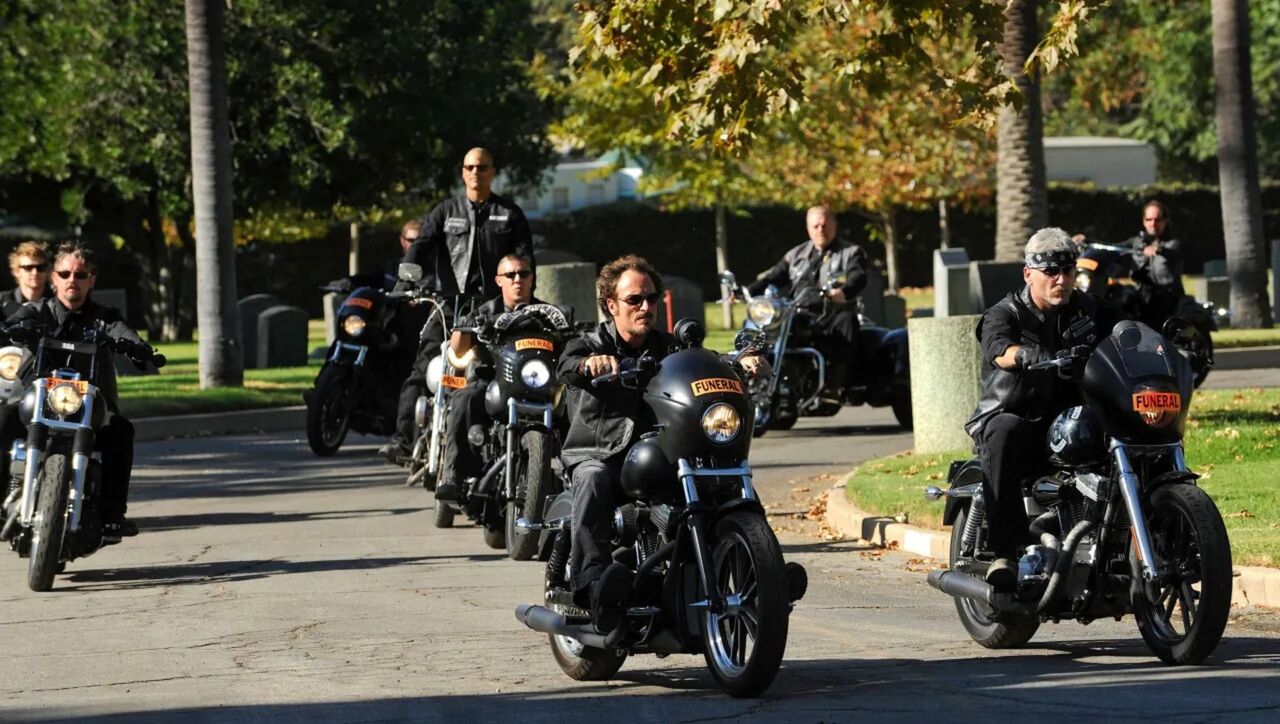 サンズ・オブ・アナーキー・バイク・クラブが自転車に乗って葬式に向かう画像。