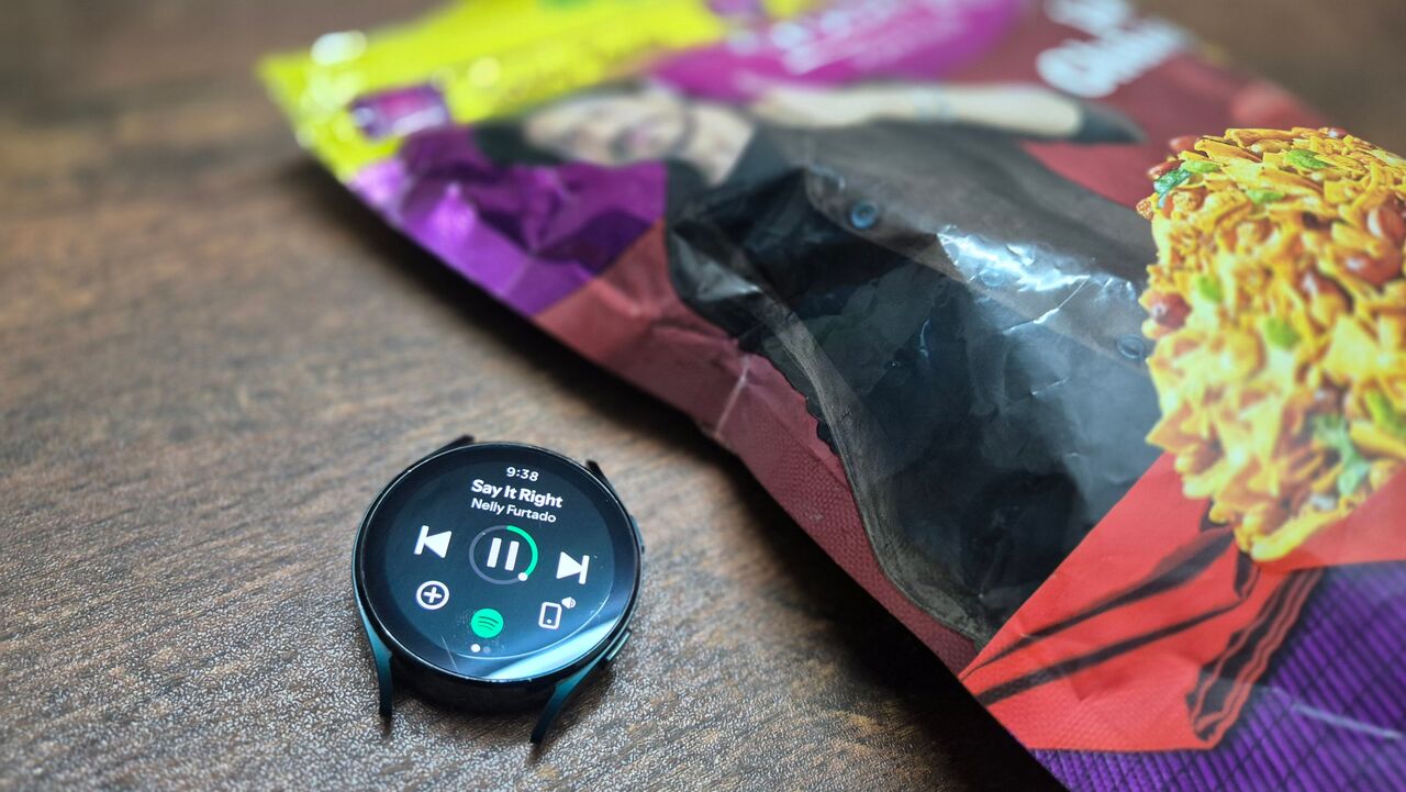 スナックの入った袋を横に置き、Spotify で音楽を再生している Samsung Galaxy Watch 4。