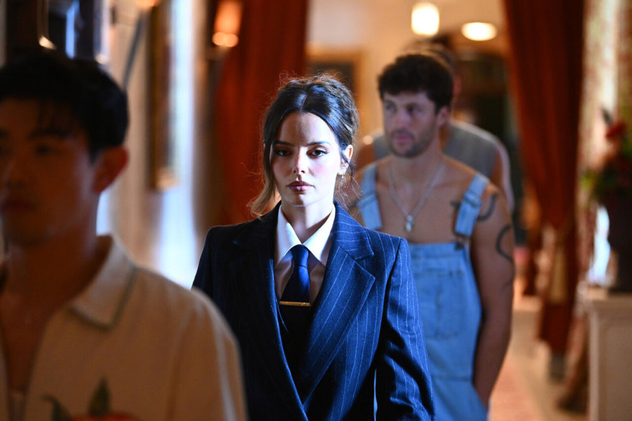 핀스트라이프 양복과 넥타이를 매고 있는 마우라 히긴스(Maura Higgins), 작업복을 입은 롭 린더(Rob Rinder)와 그 뒤에 또 다른 남자가 걸어가고 있습니다.