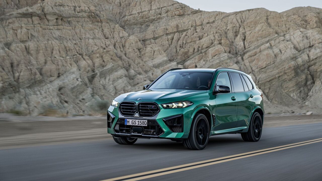 緑色の BMW X5 M Competition のダイナミックなフロント 3/4 ショット。