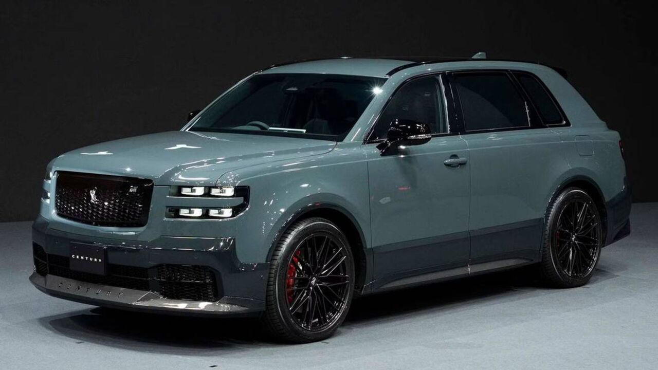 黒の背景にステージ上のグレーの 2024 トヨタ センチュリー SUV の正面図。