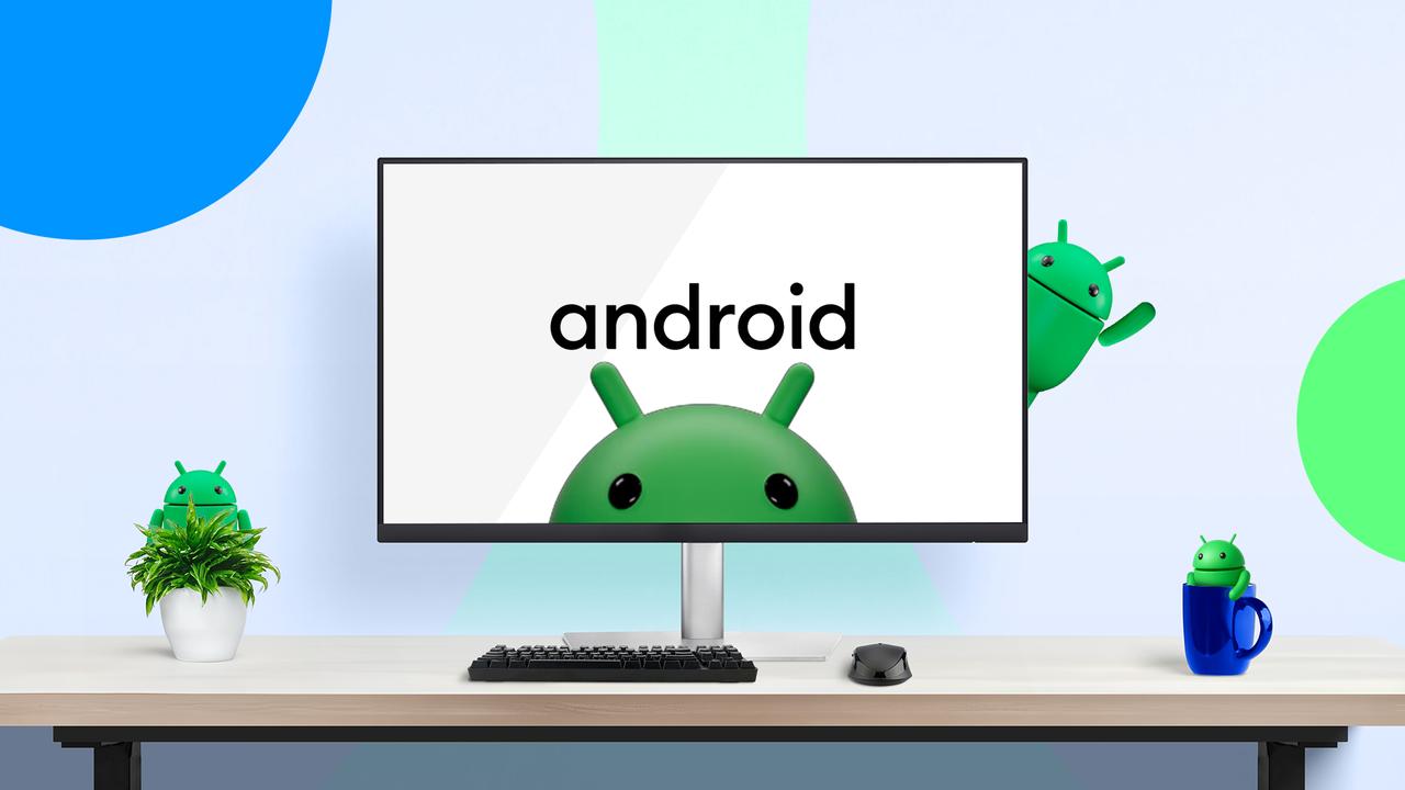 デスクトップ モニターには Android ロゴが表示され、Android マスコットが下端から覗いています。追加の Android フィギュアは、カラフルでモダンなワークスペースのデスク プラントとマグカップの上に置かれています。