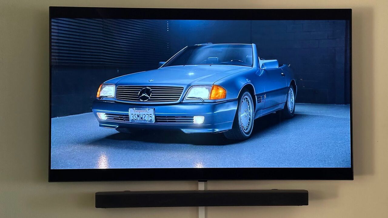 壁に取り付けられた有機ELテレビとその下にサウンドバーが付いています。テレビでは、クラシックなメルセデス SL をフィーチャーしたハガティ YouTube チャンネルのシーンが放映されています。