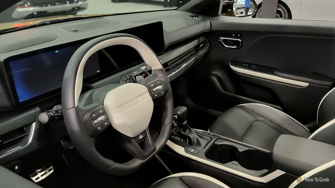 2026 Kia K4 ハッチバックのキャビン内のステアリング ホイールとダッシュボードのクローズ アップ ショット。