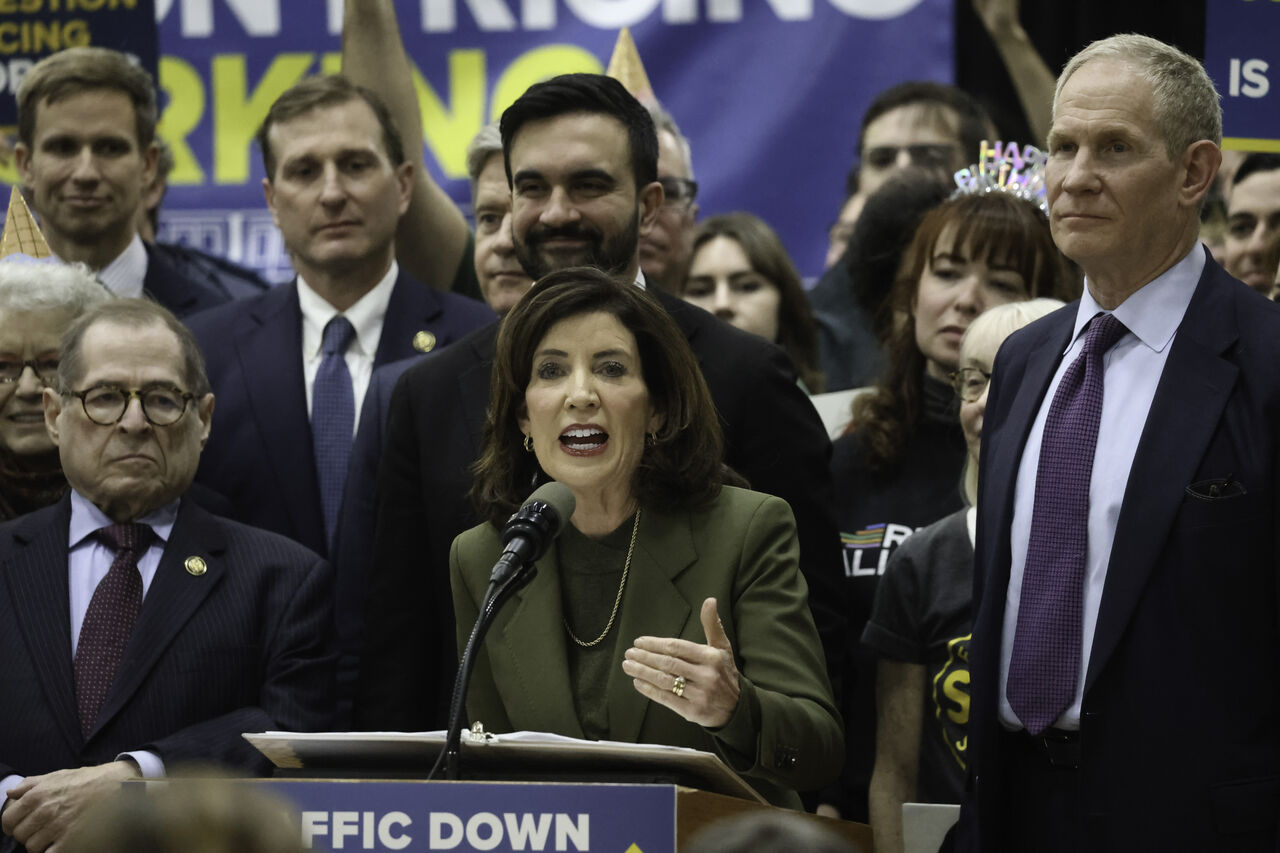 Kathy Hochul 주지사는 Zohran Mamdani 뉴욕 시장, Janno Lieber MTA CEO 및 다른 정치인들과 함께 연단에서 뉴욕시의 혼잡통행료 부과 1주년을 축하하며 연설하고 있습니다.