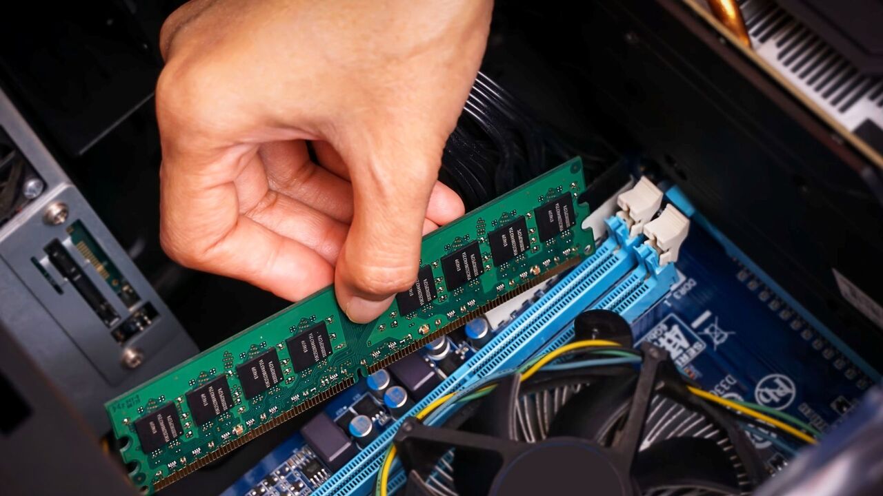 誰かがコンピュータに RAM スティックを取り付けています。