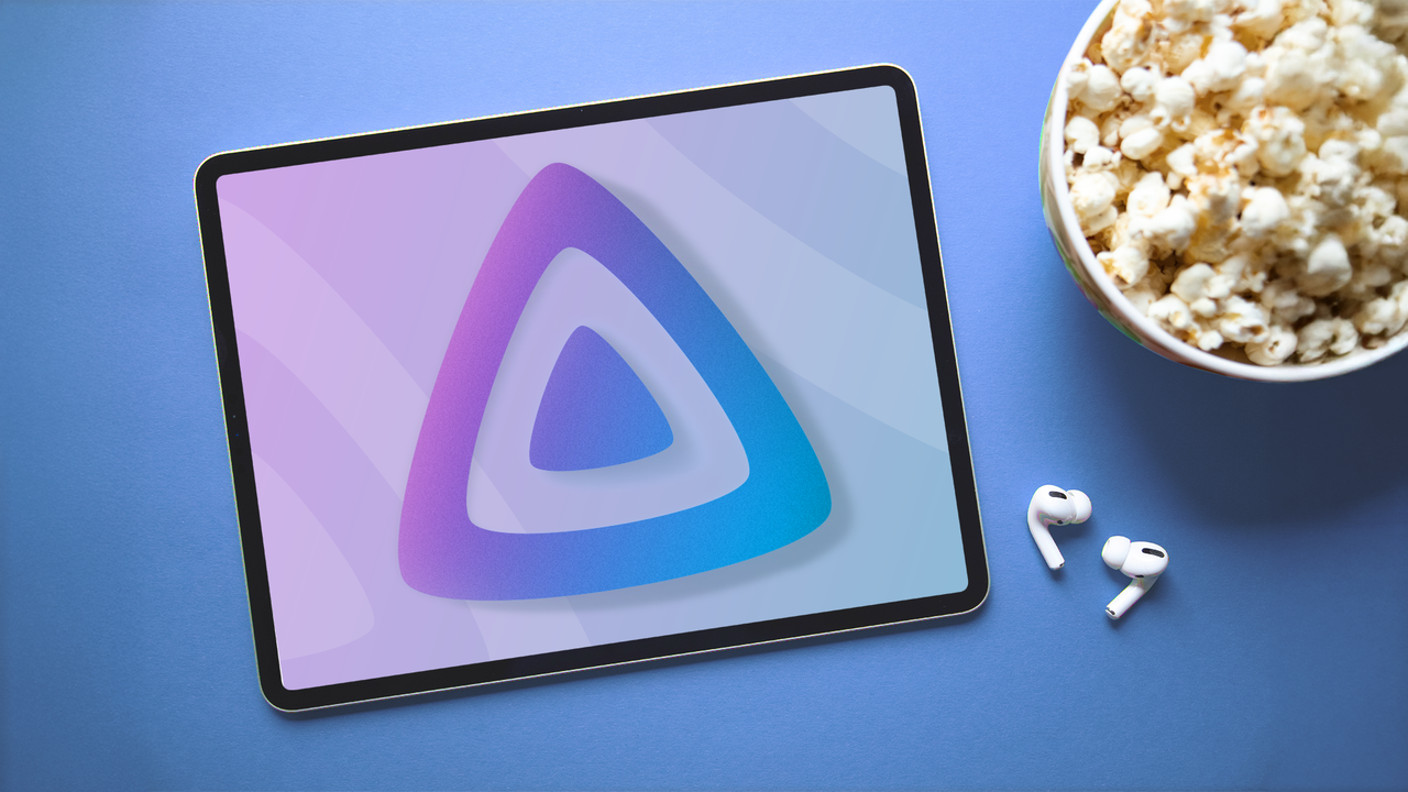 画面上に Jellyfin ロゴが表示されたタブレット。ポップコーンの入ったボウルとワイヤレス イヤホンの横に置かれています。
