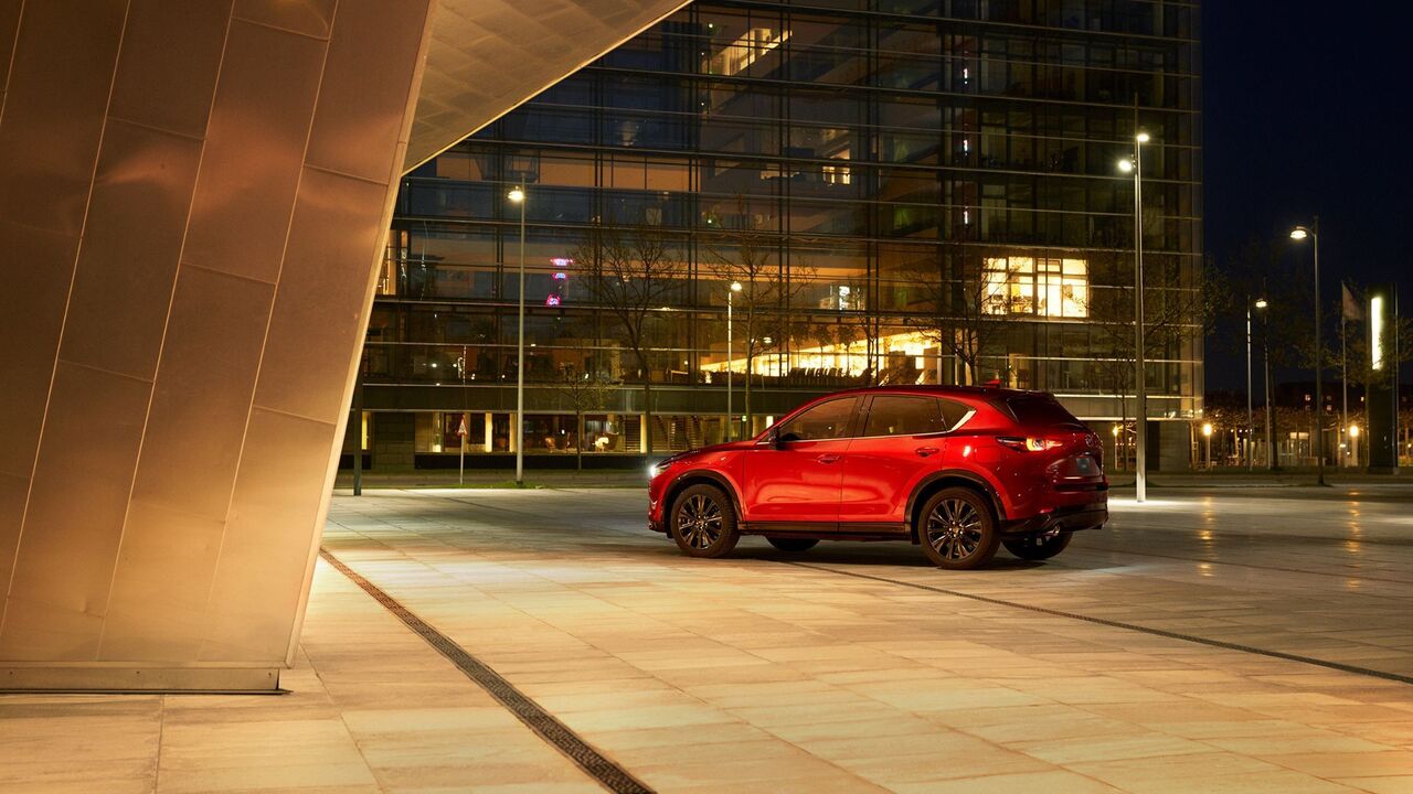 夜の街に駐車された赤い 2025 型マツダ CX-5 の後部 3 角ビュー。