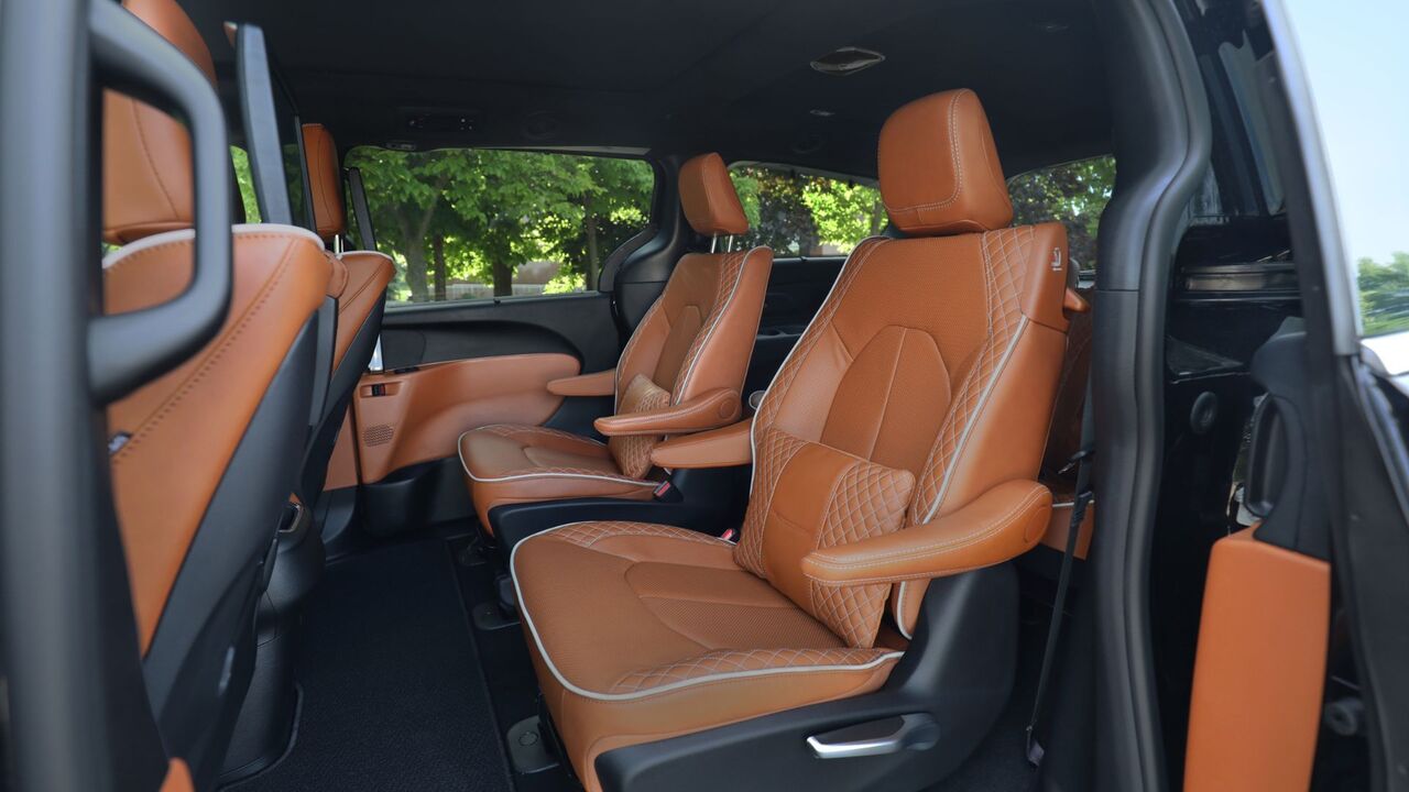 2025 年型クライスラー パシフィカ プラグイン ハイブリッド ピナクルの中央列のタン レザー シートのクローズ アップ ショット。