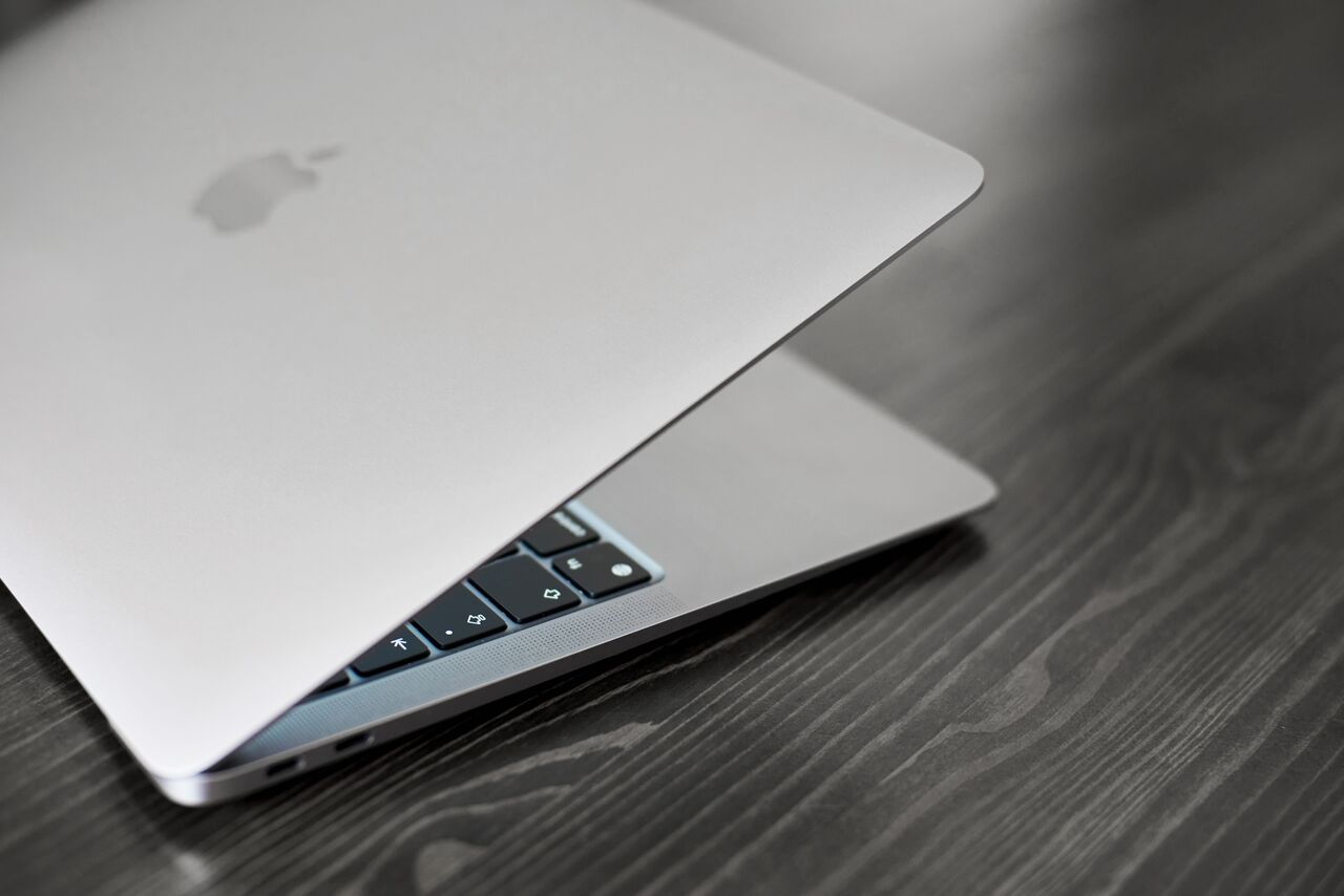 半開きの MacBook Air が木製のテーブルの上に立っています。