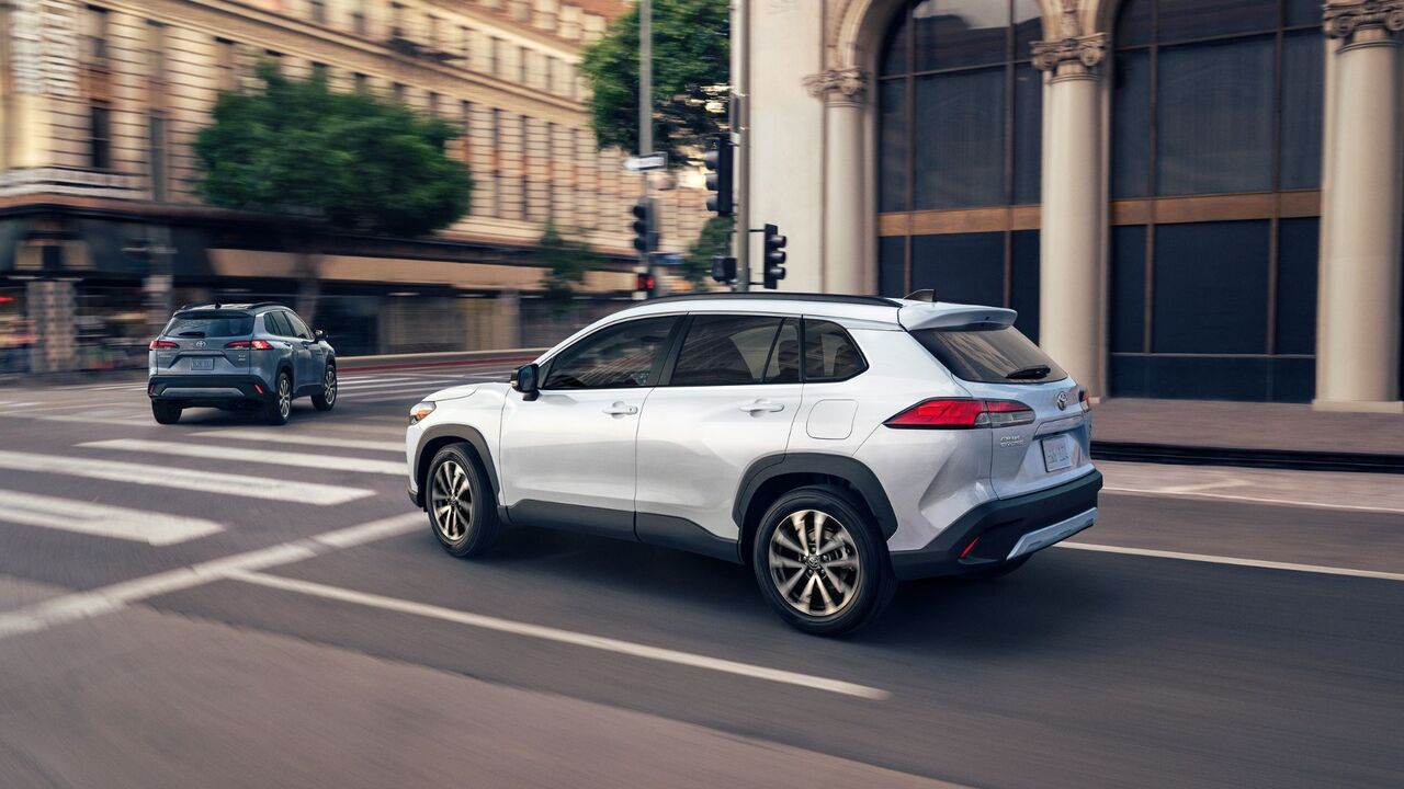 白い 2025 トヨタ カローラ クロス ハイブリッド XLE のダイナミックなリア 3/4 ショット。