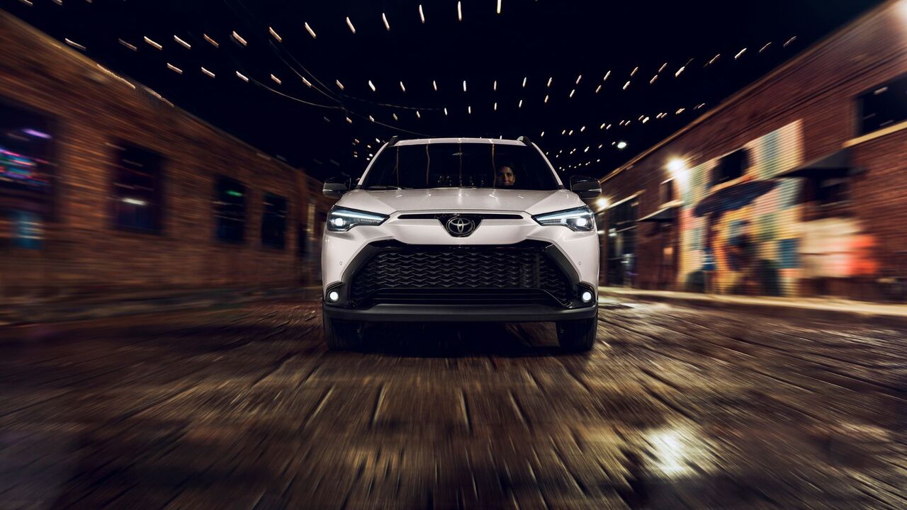 白い 2025 トヨタ カローラ クロス ハイブリッド XSE のダイナミックなフロントエンド ショット。