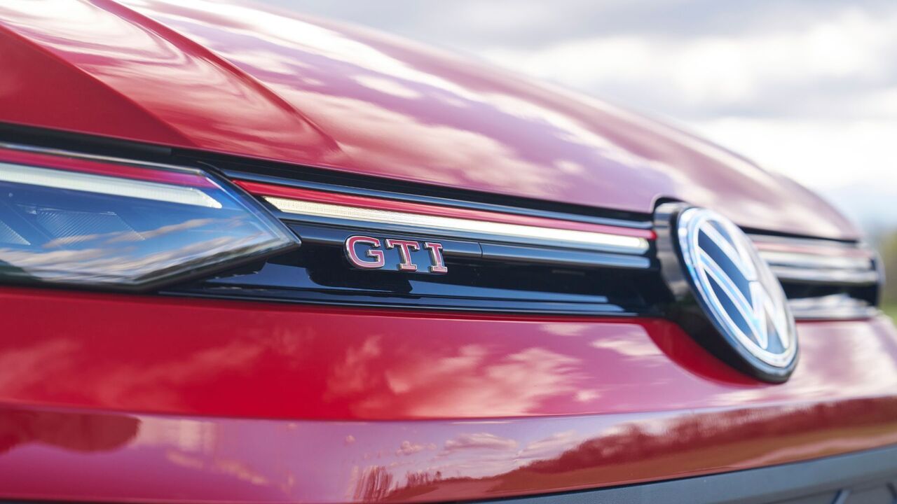 赤い 2025 年型フォルクスワーゲン ゴルフ GTI アウトバーンのグリルにある GTI バッジのクローズ アップ ショット。