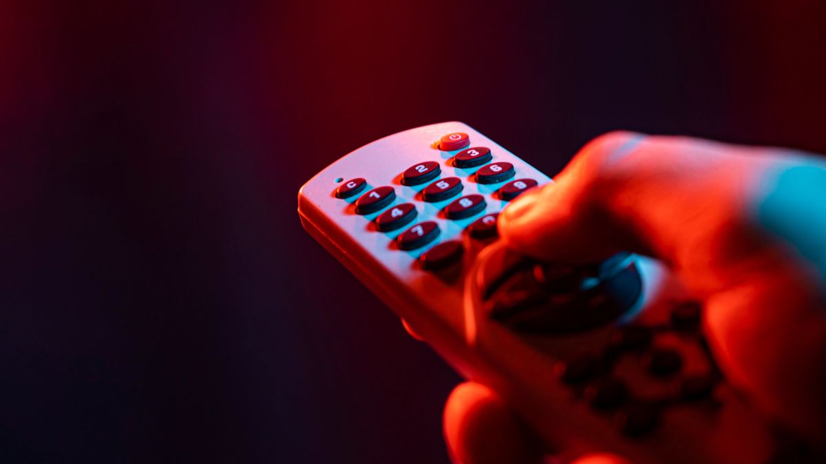 IR テレビのリモコンのボタンを押す手。